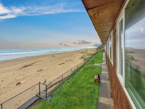 A beach view from a balcony with a grassy area and a fence.