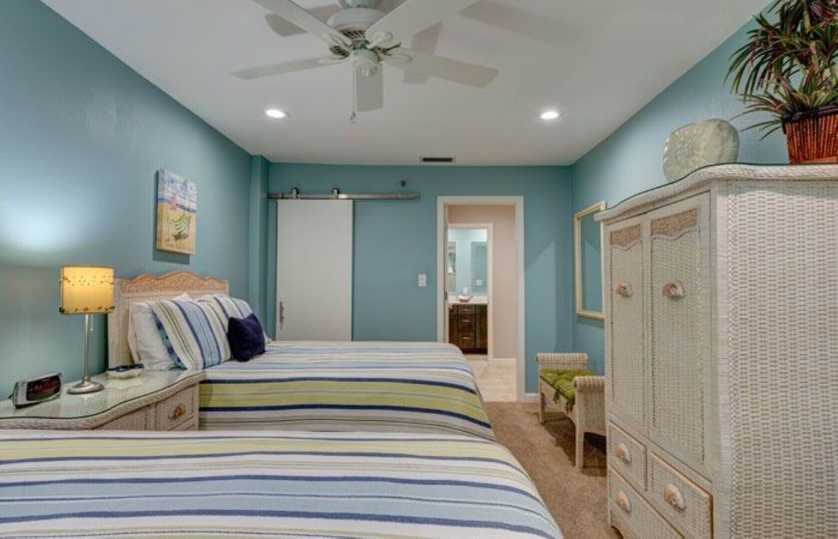 Quarto com cama, mesa de cabeceira, cômoda e ventilador de teto.