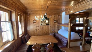 A wooden cabin interior with a wooden table, benches, and a bunk bed. - Casa San Barnaba (Cortina d'Ampezzo)