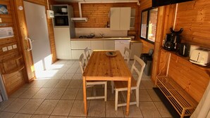 Une cuisine compacte avec un coin repas, des murs en bois, un four à micro-ondes, un évier et un grille-pain.