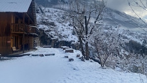 Une cabane en bois dotée d’un balcon, un paysage enneigé et une montagne en arrière-plan.