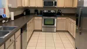 A modern kitchen with stainless steel appliances, beige cabinetry, and a tiled floor. -  The Wilson Wilds, A Peaceful 4BR Family Retreat, Private Pool 15 Mins to Disney (Davenport)
