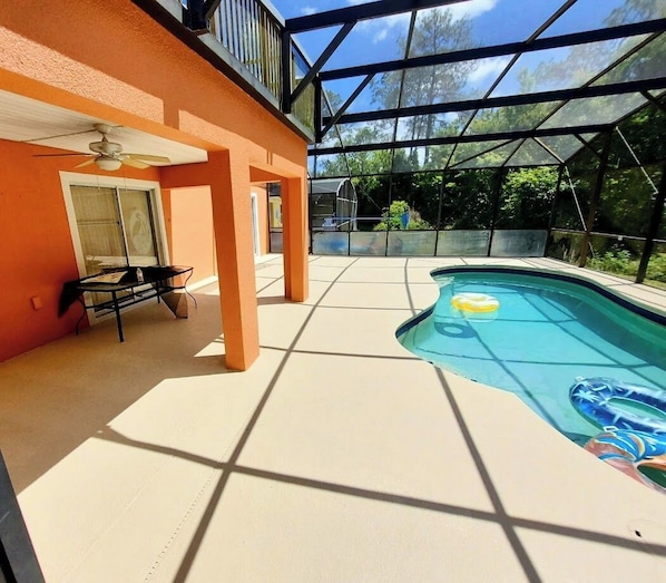 A swimming pool with a glass enclosure, a ceiling fan, and a table with chairs. - The Wilson Wilds (Davenport)