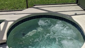 A hot tub with a curved edge, surrounded by a concrete deck and a metal fence. -  The Wilson Wilds, A Peaceful 4BR Family Retreat, Private Pool 15 Mins to Disney (Davenport)
