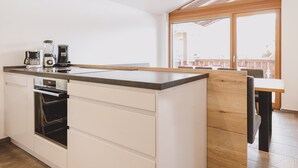 Moderni keittiö, jossa on sisäänrakennettu uuni ja kahvinkeitin.