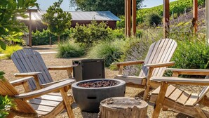 A patio area with Adirondack chairs, a fire pit, and a rustic wooden table.