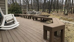 Een houten terras met bankjes en een vuurkuil.