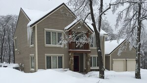 Een tweelaags huis met een veranda, een garage en een sneeuwbedekte voortuin.