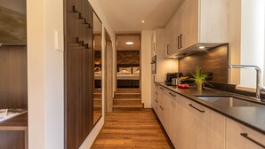 A modern kitchen with wooden flooring, a black countertop, and a built-in stove. - Tevini Boutique Suites - Apartment Water, balcony (Zell am See)