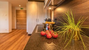 A kitchen counter with a potted plant, a pot of spaghetti, and a bunch of tomatoes. - Tevini Boutique Suites - Apartment Earth, balcony (Zell am See)