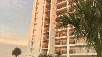 Un hotel de gran altura con varios balcones, una piscina y abundante vegetación.