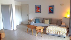 Una sala de estar con un sofá, una mesa de centro y dos cuadros en la pared.