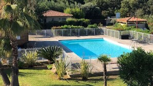 Una piscina rodeada por un área cercada con palmeras y un edificio al fondo.
