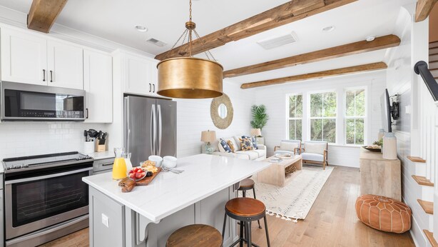 A modern kitchen with white cabinets, stainless steel appliances, and a large island with stools.