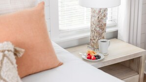 A neatly arranged bedroom with a bed, a bedside table with a lamp, and a small plate of fruit.