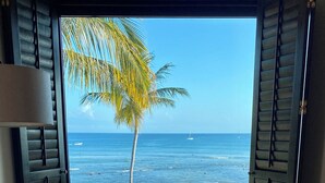 Ein Zimmer mit Blick auf Strand und Meer durch geöffnete Fensterläden.