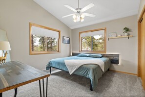 A bedroom with a bed, a desk, and a ceiling fan.