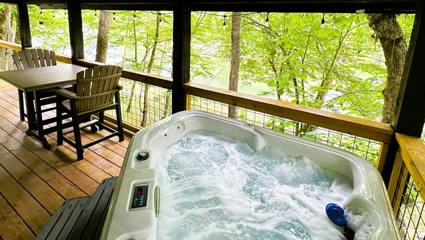 Ein Whirlpool auf einer Holzterrasse mit Blick auf Bäume.