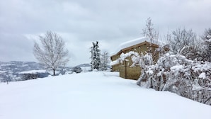 A snow-covered landscape with a stone building, bare trees, and distant hills. - Fonte Rosa farmhouse with pool (Fiastra)