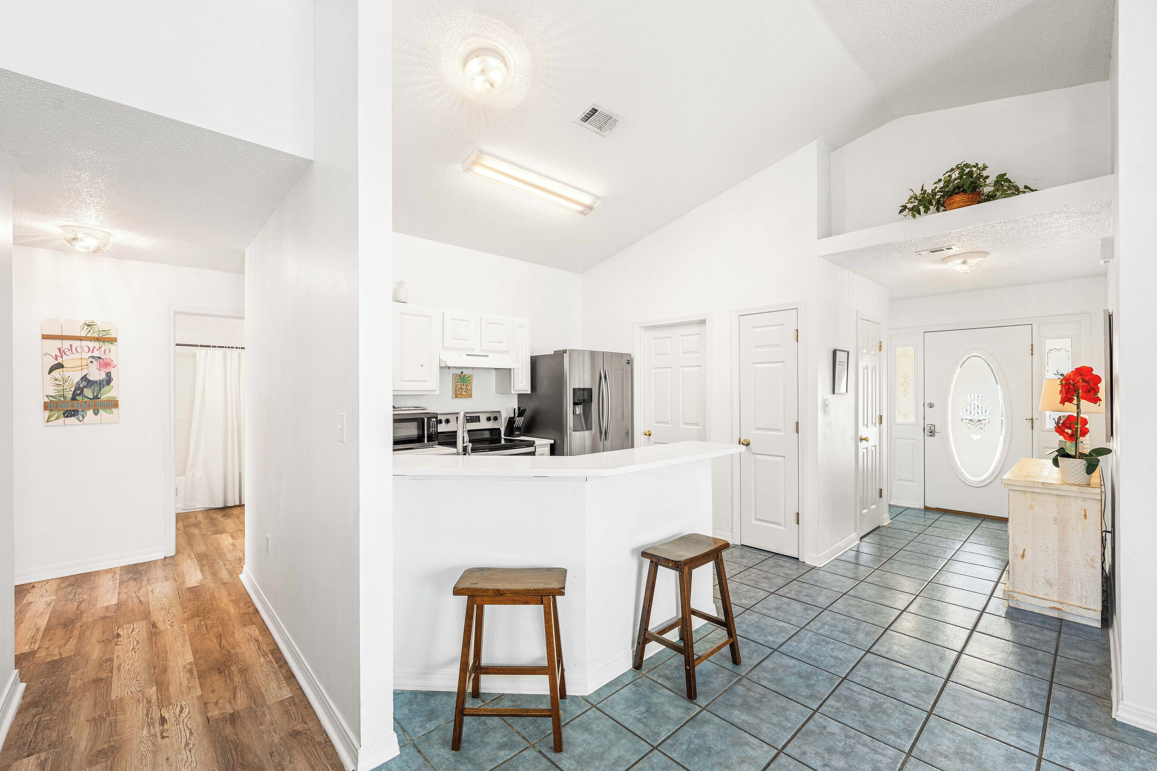 A spacious kitchen with white cabinets, a stainless steel refrigerator, and a central island with stools.