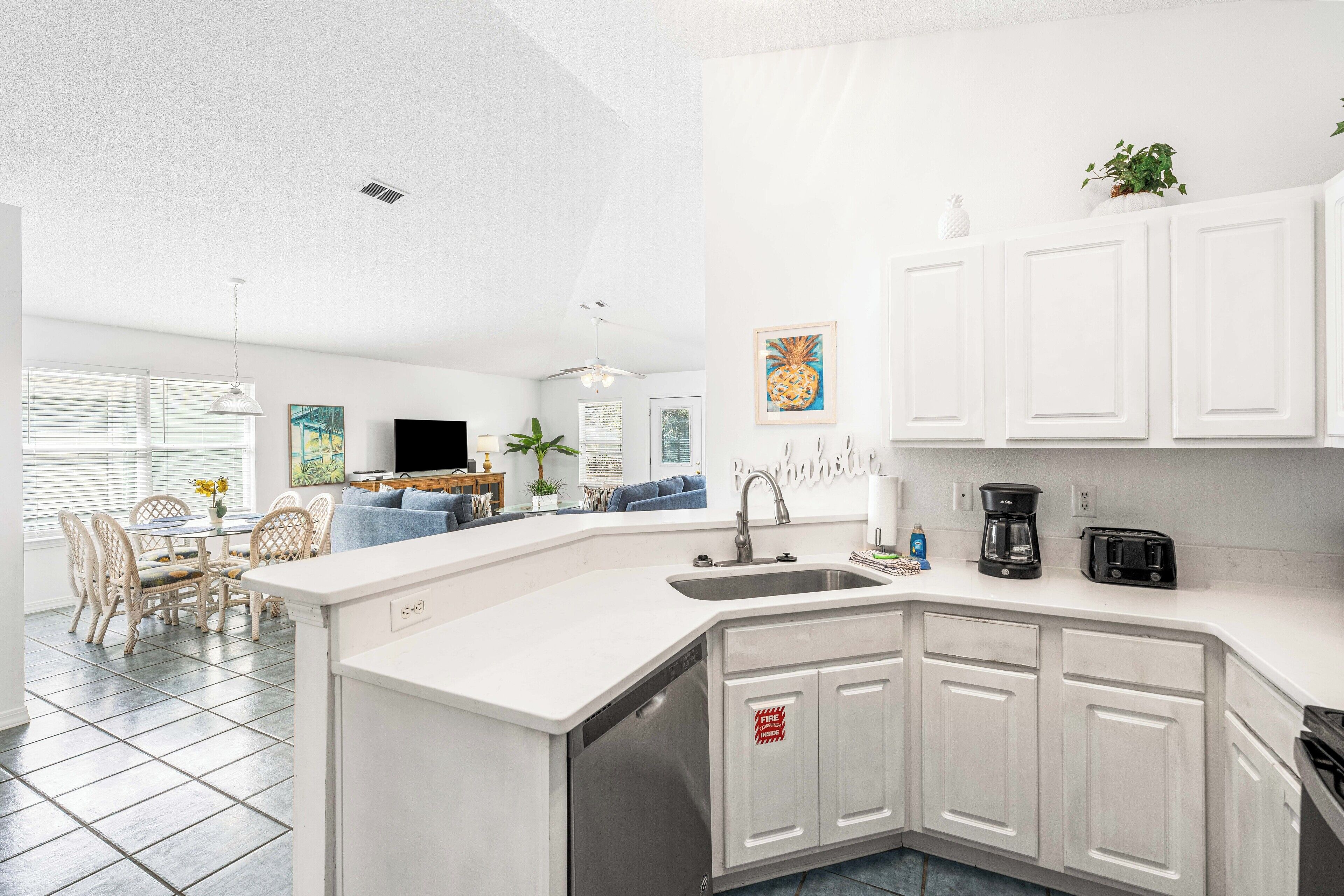 A modern kitchen with white cabinetry, a built-in dishwasher, and a coffee maker.