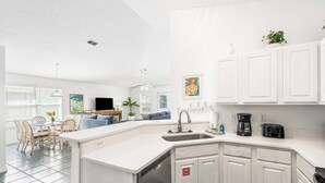 Una cocina moderna con armarios blancos, lavavajillas integrado y cafetera.