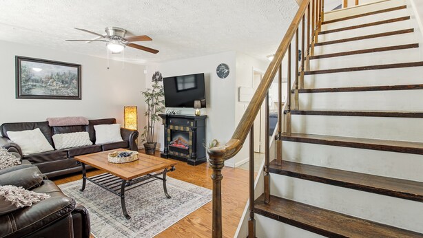 A living room with a fireplace, a sofa, a coffee table, and a staircase.
