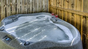 A hot tub with a wooden fence in the background.