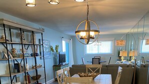 A kitchen with a marble countertop, wooden cabinets, a dining area with a table and chairs, and a bookshelf. - Spacious Beachfront Condo Located on Grand Lagoon  (Panama City)