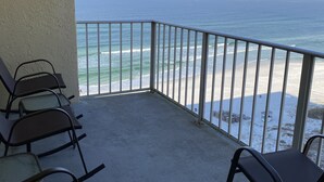 A balcony with metal railings overlooking a beach with waves and a clear sky. - Spacious Beachfront Condo Located on Grand Lagoon  (Panama City)