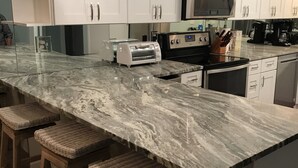 A modern kitchen with white cabinets, a marble countertop, and a built-in microwave. - Spacious Beachfront Condo Located on Grand Lagoon  (Panama City)