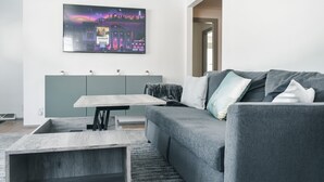 Un salon moderne avec un canapé gris, une table basse en bois et un meuble gris.