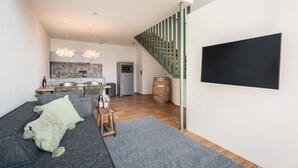 Uma sala de estar moderna com um sofá, uma mesa de centro e uma TV fixada na parede.