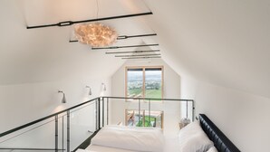 Quarto moderno com uma janela grande, uma escada e vista para o exterior.