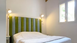 A bedroom with a bed, a nightstand, a lamp, and a window.