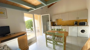 A compact kitchen with a dining area, a washing machine, and a television.