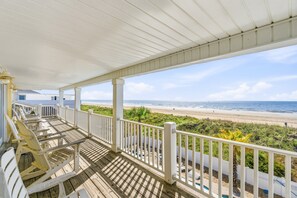 A wooden deck with white railings overlooking a beach.
