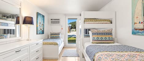 A bedroom with two beds, a dresser, a mirror, and artwork on the walls.