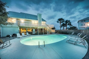 A residential property with a swimming pool, outdoor seating, and a staircase leading to a balcony.