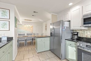 A modern kitchen with white cabinets, a stainless steel refrigerator, and a built-in oven.