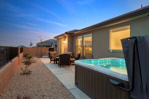 A backyard with a hot tub, patio furniture, and a covered seating area.