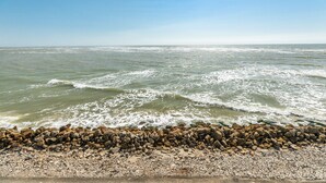 A beach with waves crashing onto a rocky shore under a clear sky.
