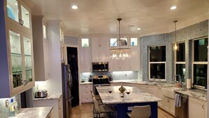 A modern kitchen with a marble island, stainless steel appliances, and a patterned backsplash.