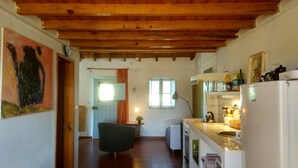 A compact kitchen with wooden beams, a dining area with a chair, and a small table with a plant. - Nice country studio for 2-4p., shared pool, countryside&beach (20 km) (cercal do alentejo)