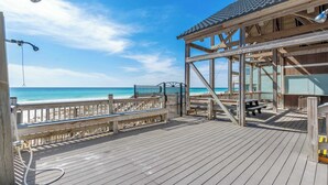 Eine Holzterrasse mit Blick auf Strand und Meer.