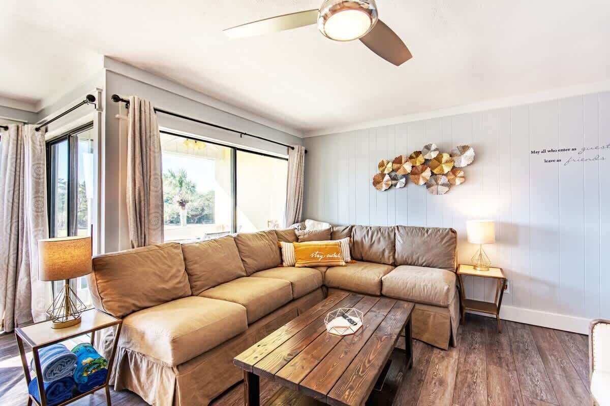 A modern living room with a sectional sofa, a wooden coffee table, and a ceiling fan.