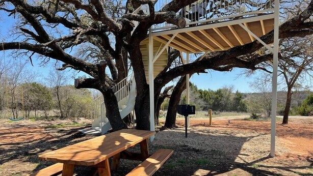 Une table de pique-nique sous un arbre, avec un espace de repos abrité.