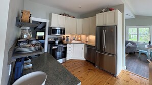 Una cocina moderna con armarios blancos, electrodomésticos de acero inoxidable y piso de madera.