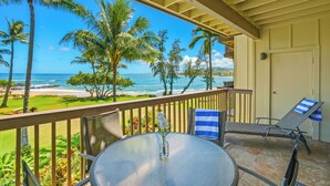 A balcony with a table and chairs, overlooking a beach and ocean. - "Magical View" oceanfront condo Lae Nani #521 (Kapaa)