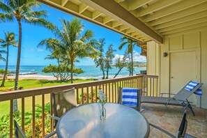 Enjoy the ocean view from this balcony with a round table and comfortable seating for two.